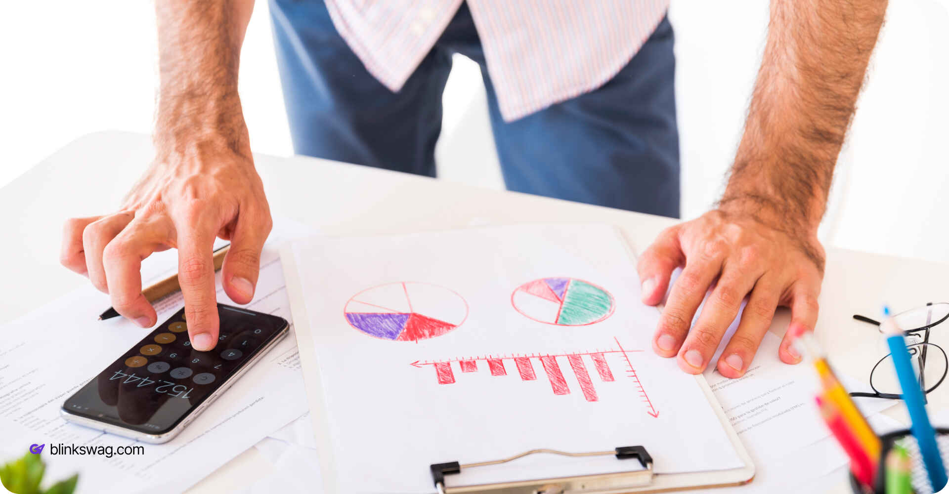 a man calculating on phone with some pie charts on paper in front
