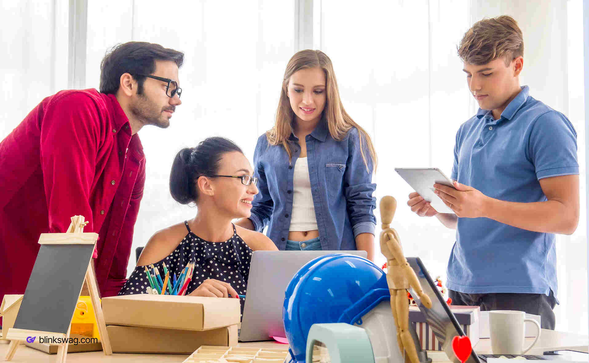 How to Create the Perfect Onboarding Kit with Branded Company Swag 1 A group of people in a office working together with boxes on table