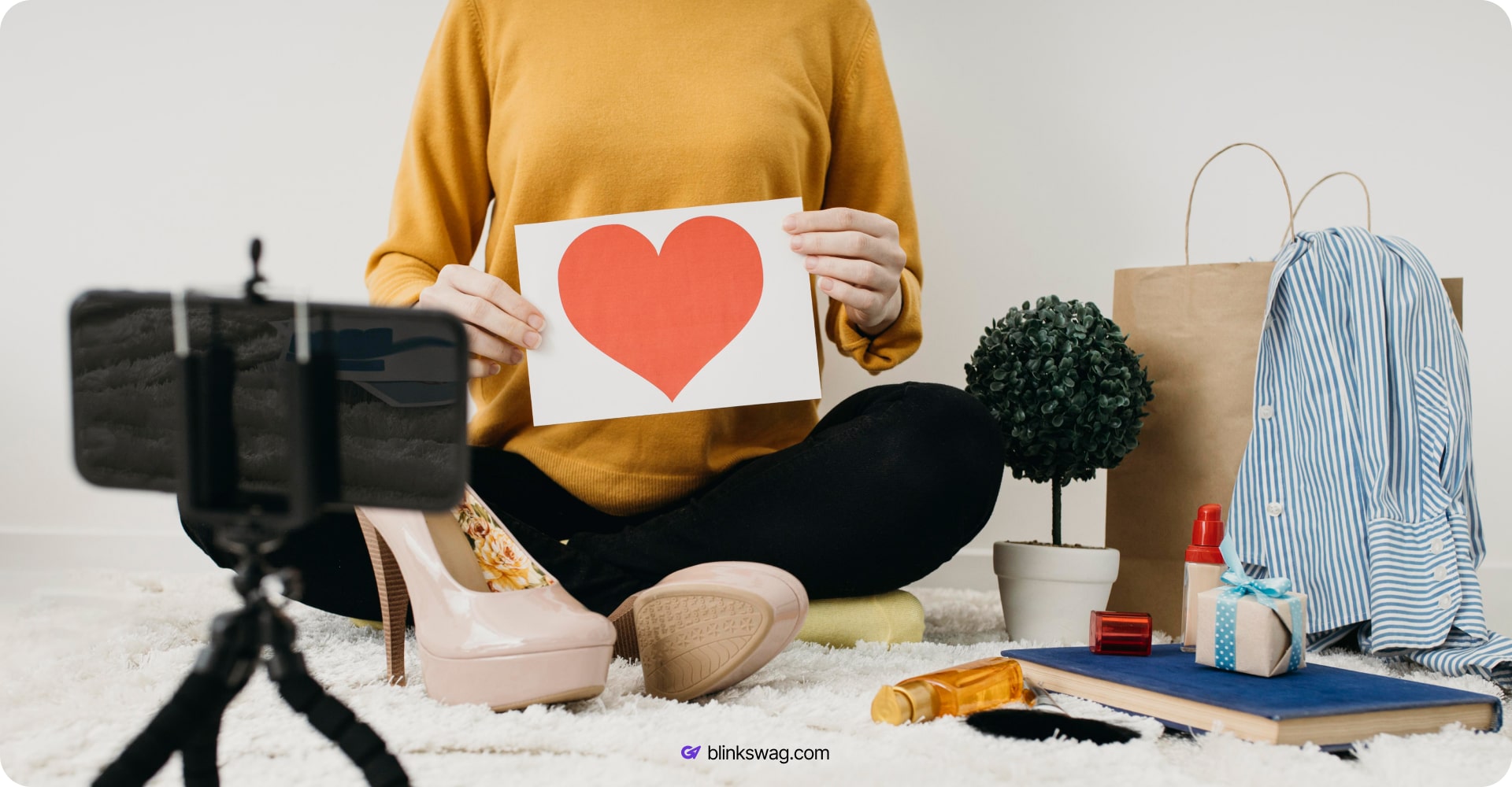 a woman holding a heart drawing with some merch around her